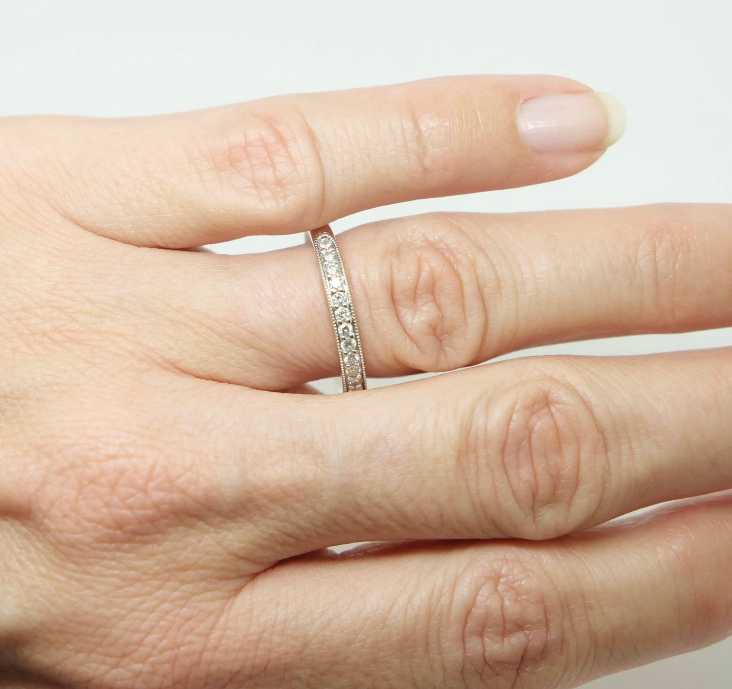 18ct white gold diamond half eternity ring, set with round brilliant cut diamonds across the top half of the band and edged with fine milgrain detail along both sides